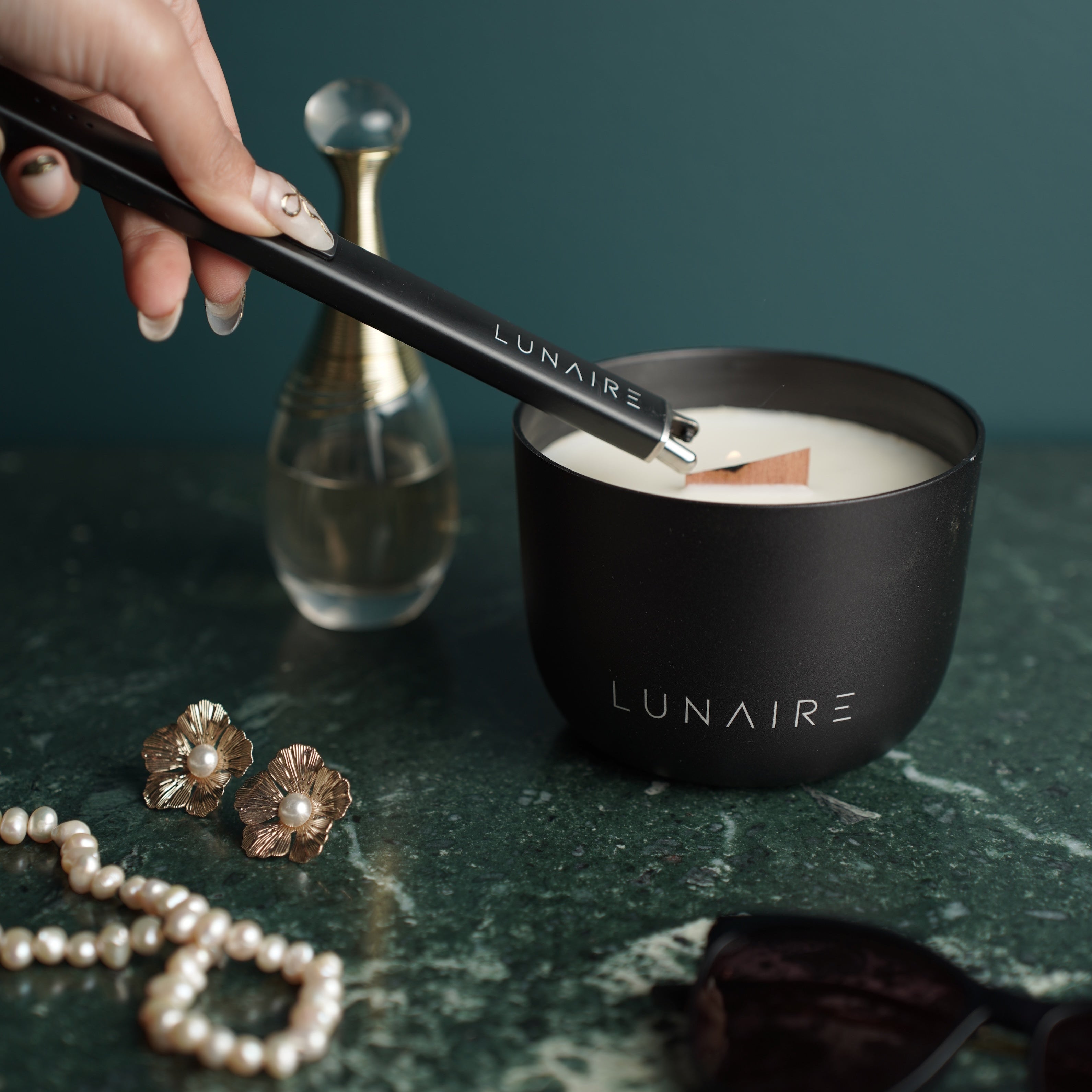 Lunaire Aluminium Black Candle on a bedside table with other luxury items 