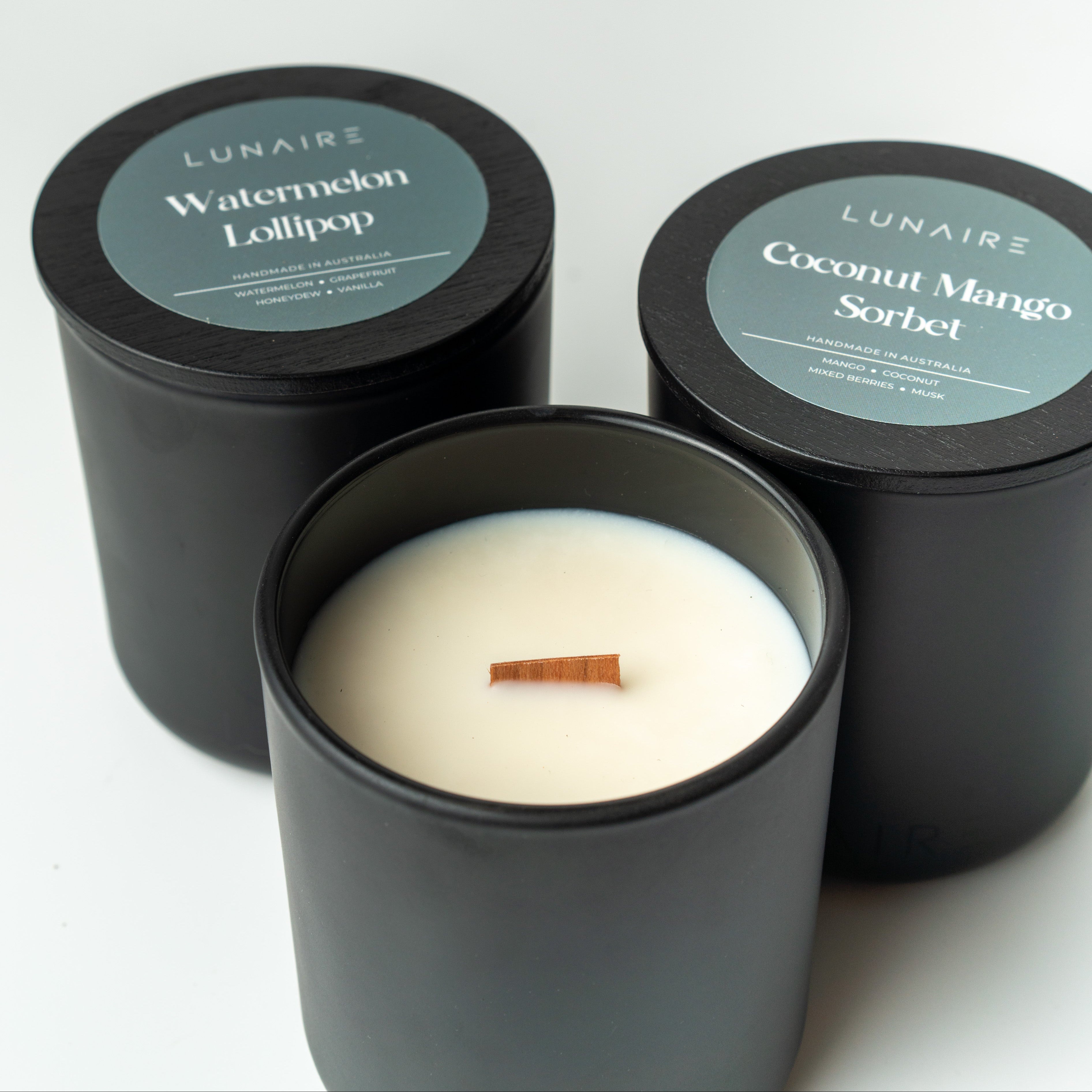 Three black  vegan soy candles with labels on a white background
