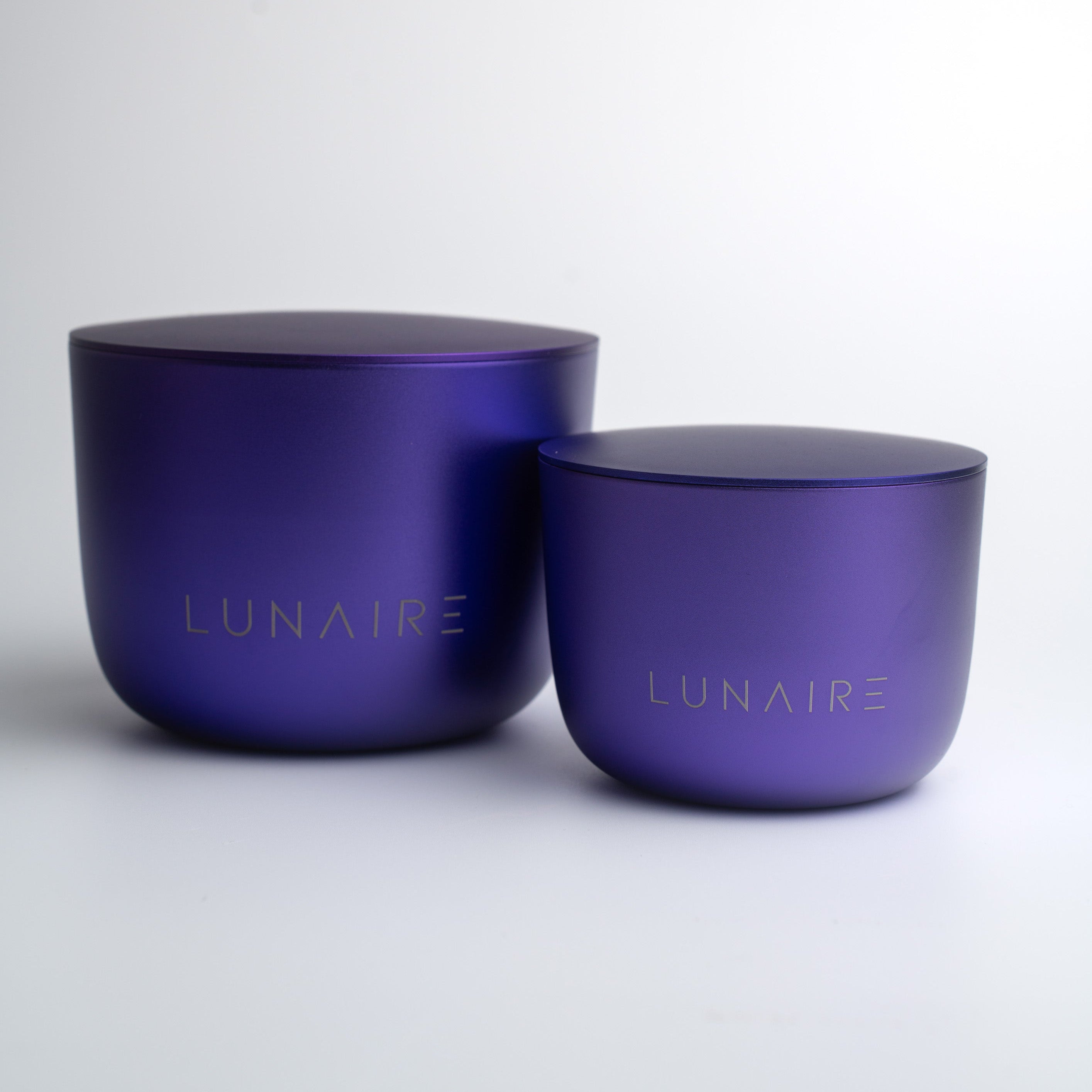 Two purple aluminium candle jars with 'LUNAIRE' branding on a white background