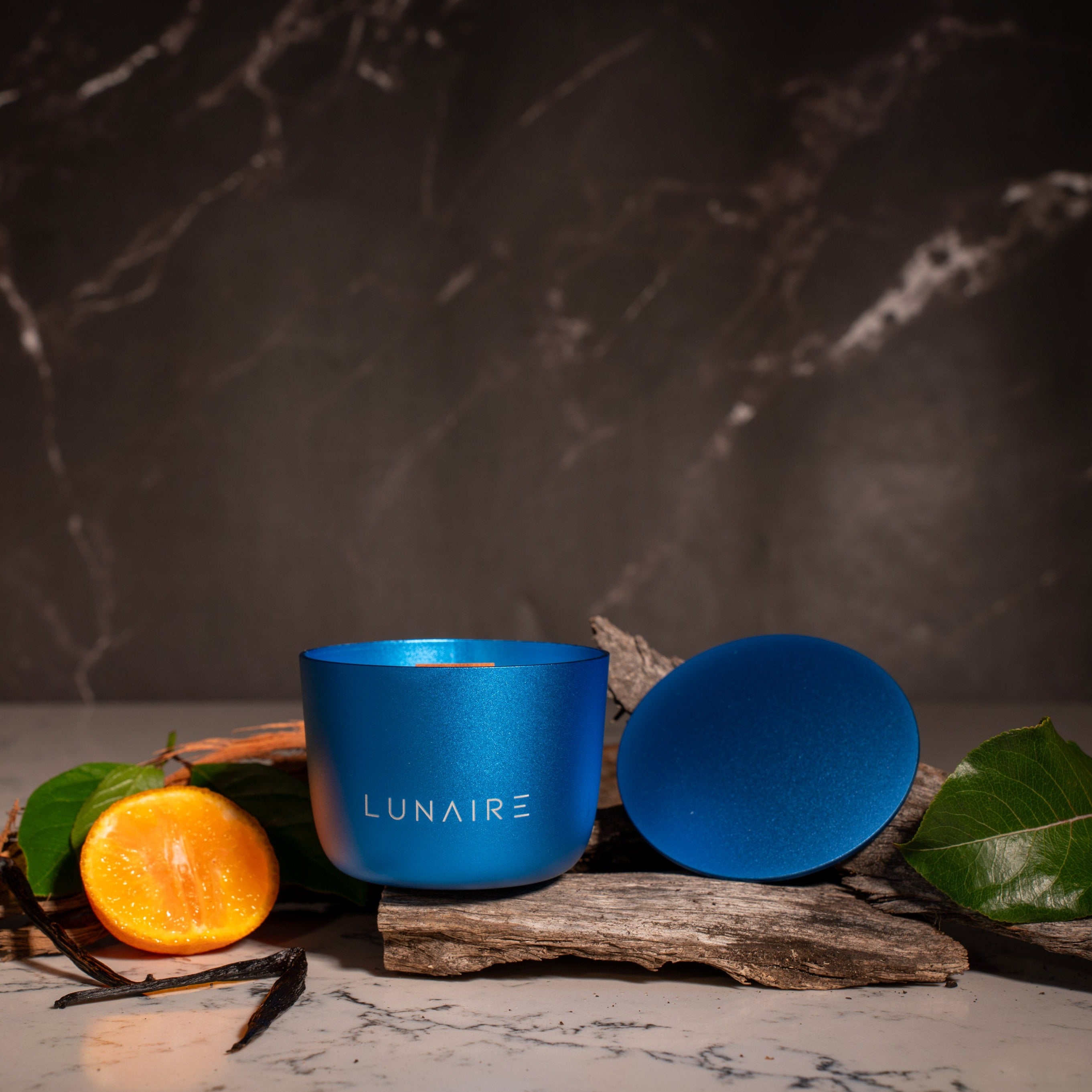 Blue Lunaire Candle with Vanilla Bean, oud, Patchouli and bergamot in the background