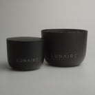 Two black candle aluminium jars with 'LUNAIRE' branding on a gray background