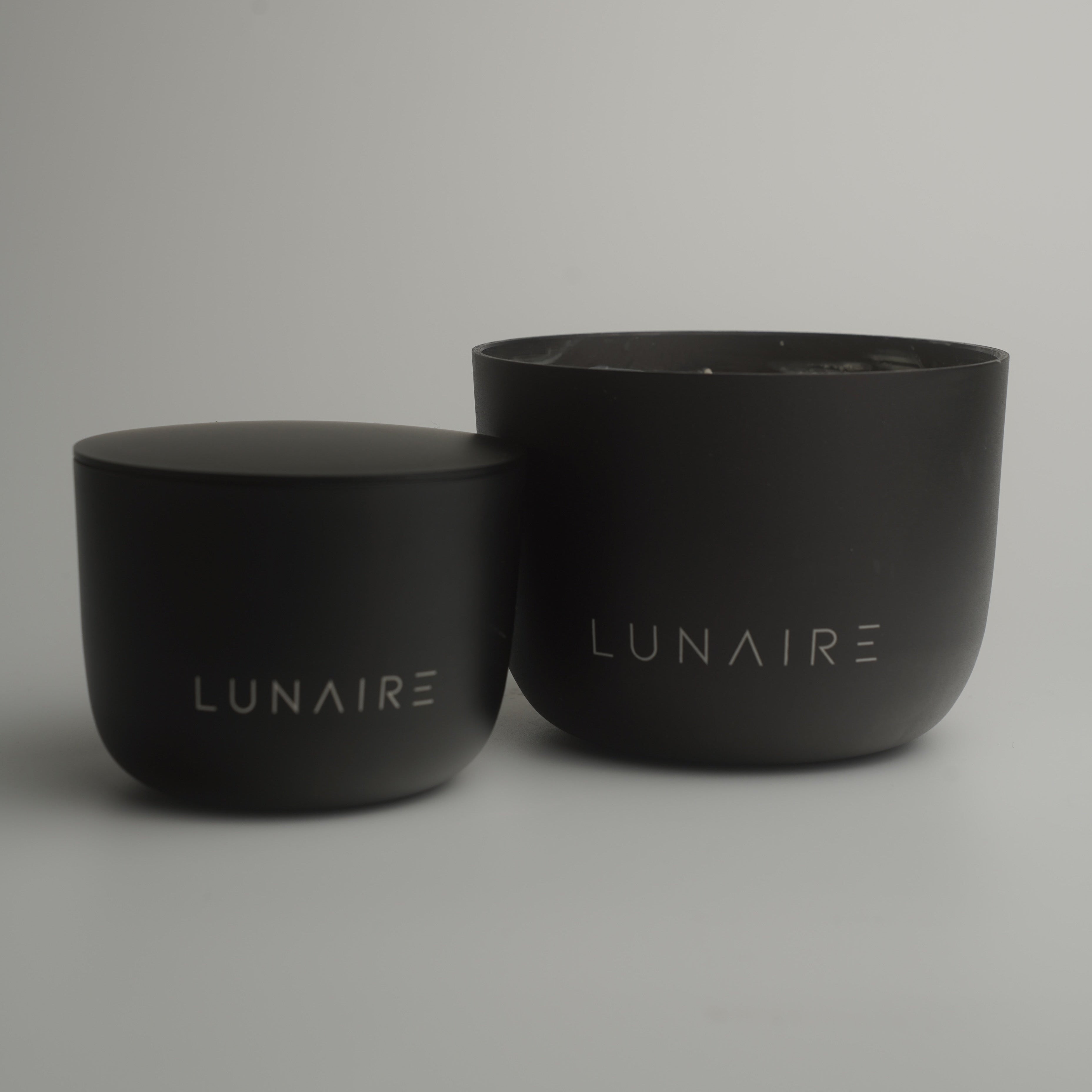 Two black candle aluminium jars with 'LUNAIRE' branding on a gray background