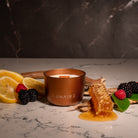 Bronze Lunaire Neptune Candle with Honeycomb, mixed berries and lemon in the background