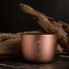 Rose gold cup with horse engraving on a dark surface with wooden elements