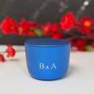 Blue candle with 'B & A' initials on a blurred floral background