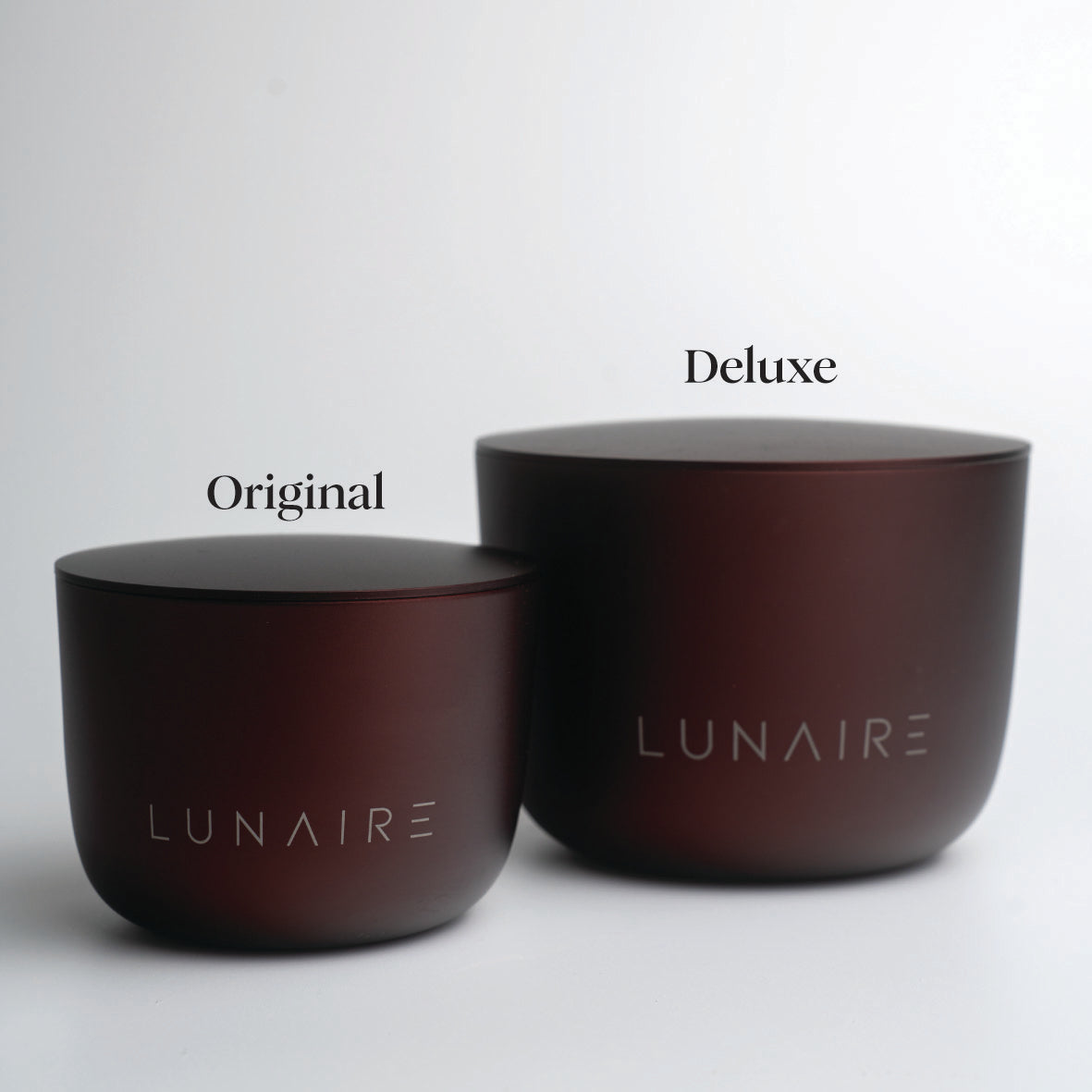 Two burgundy aluminium candles labeled 'Original' and 'Deluxe' by LUNAIRE on a light gray background.
