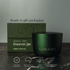 Green candle vessel and packaging with 'LUNAIRE' branding on a dark surface.