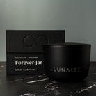 Black candle vessel and packaging with 'LUNAIRE' branding on a dark surface.