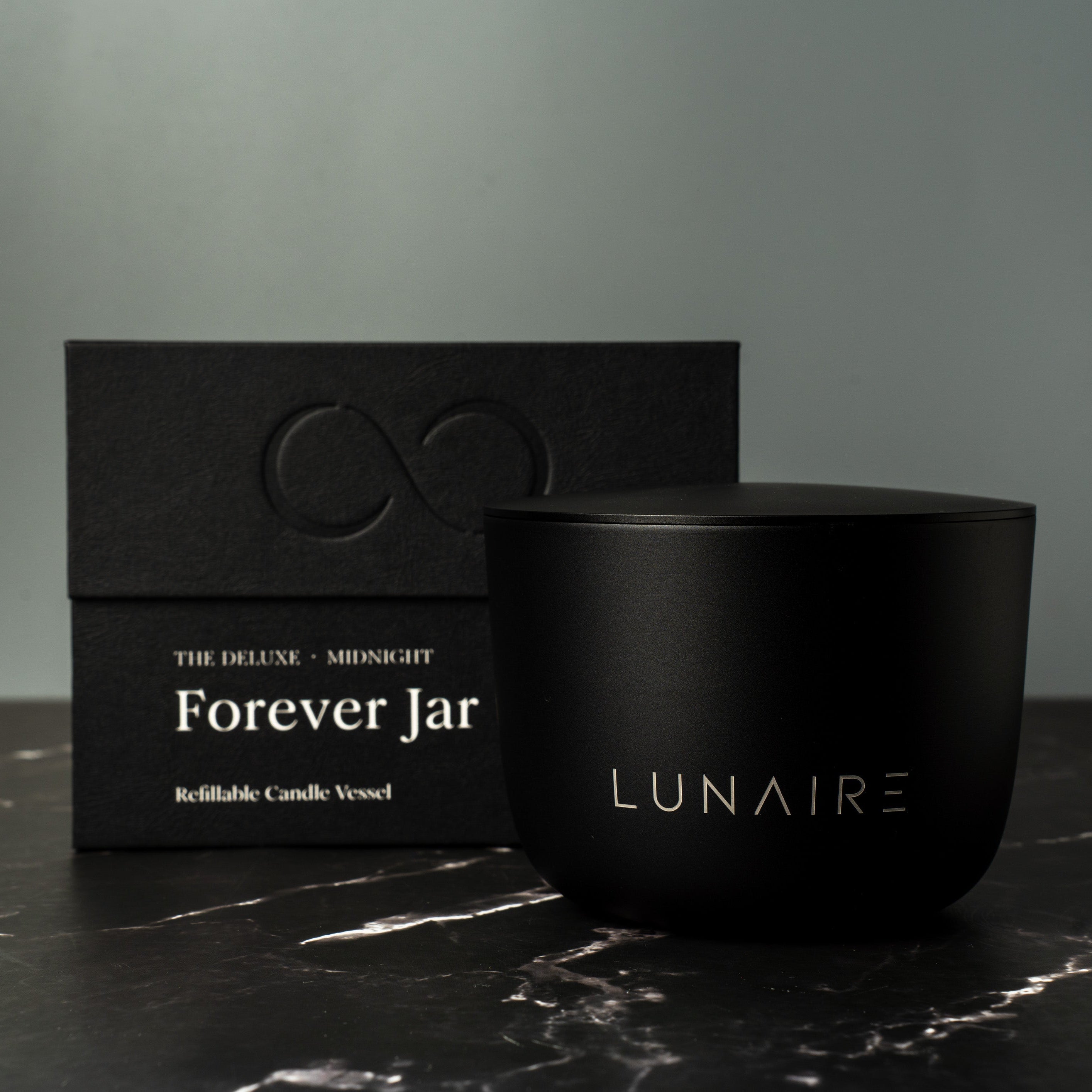 Black candle vessel and packaging with 'LUNAIRE' branding on a dark surface.