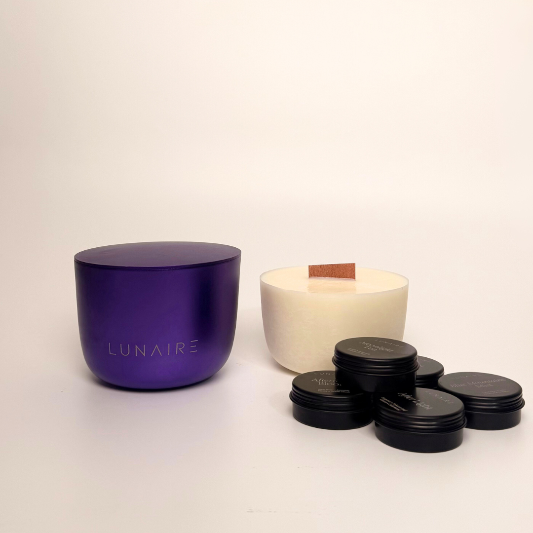 Purple aluminium candle jar  with 'LUNAIRE' branding, beige soy candle refill, and black tealight candles on a light background