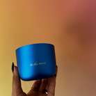 Blue candle with 'to the moon' text held by a hand against a gradient background